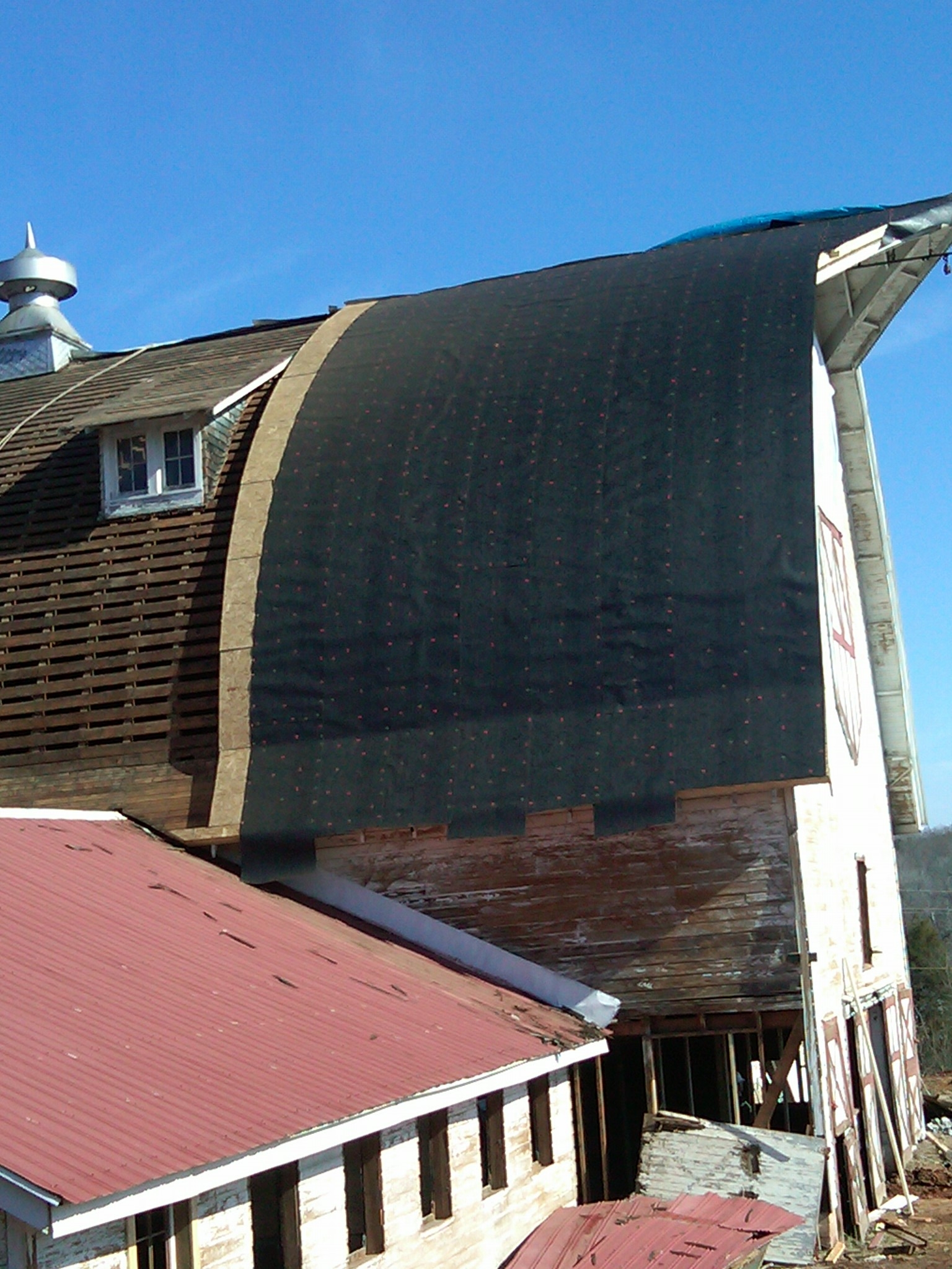 The barn's roof is being carefully removed and replaced, section by section