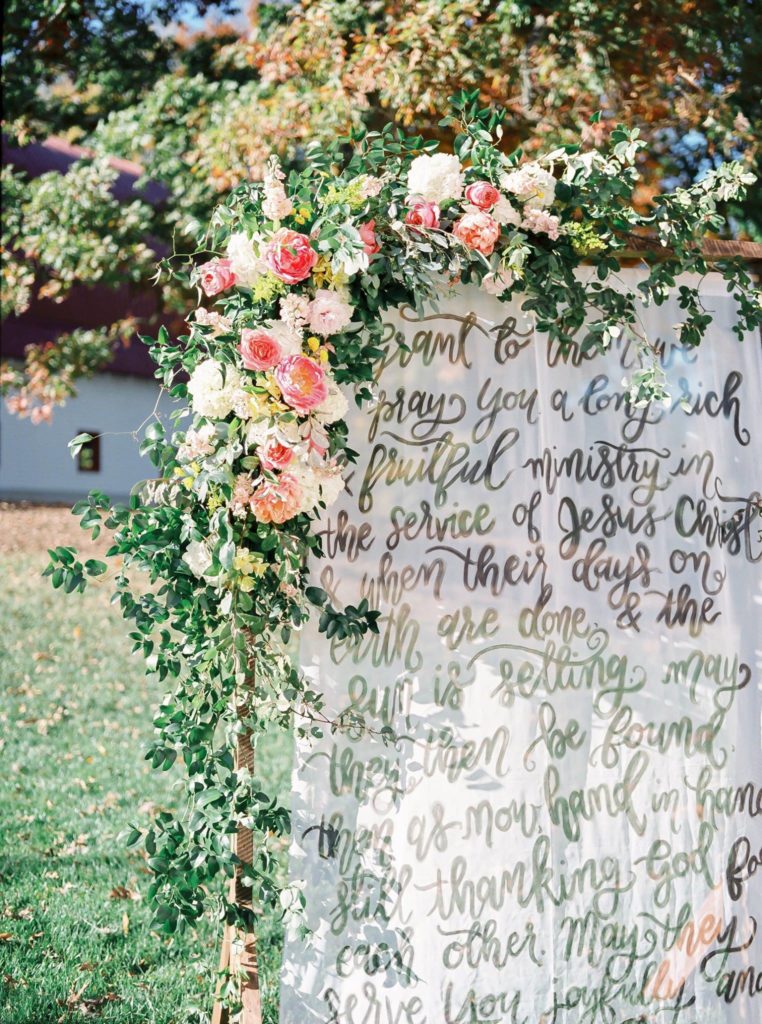Semi-transparent wedding signage covered in elaborate blooms