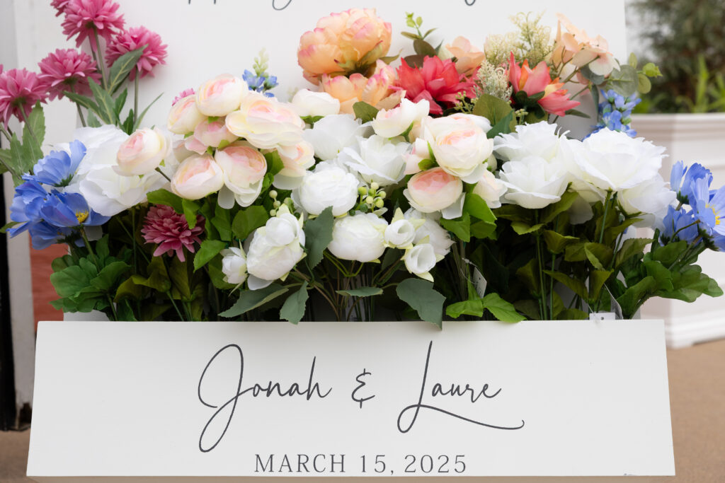 A welcome sign from a wedding at WinMock on March 15, 2025 filled with bold colored flowers that are on trend for this year.